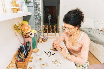 Jewelry designer working in studio, young woman creating handmade earrings