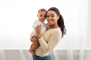 Wall Mural - Black Mom Holding Little Infant Smiling To Camera Posing Indoors