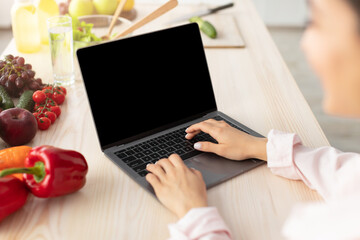 Poster - Woman using pc with empty screen for mockup in kitchen