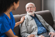© InsideCreativeHouse - Young friendly african female caregiver talking chatting to happy senior man in hallway of nursing home. Picture of smiling nurse assisting senior elderly man