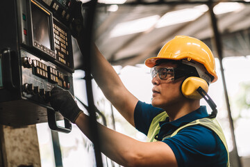 Work at factory.Asian worker man  working in safety work wear with yellow helmet and glasses l ear muff using equipment.male mechanical asia in factory workshop industry machine professional