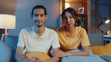 Poster - Happy young asia couple man and woman looking at camera smile and cheerful on video call online at night in living room at home, Stay at home quarantine, married life, Social distancing concept.