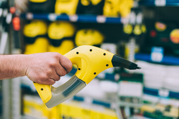 Wall Mural - A man in a hardware store holds a garment steamer.