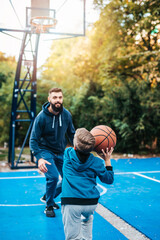 Wall Mural - Father and his son enjoying together on basketball court.