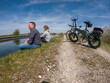 Young couple making brake at the riverside while bike trip