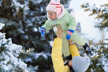 family portrait in the winter forest, mother lift the baby up in her arms, bright snowy fir trees, beautiful nature