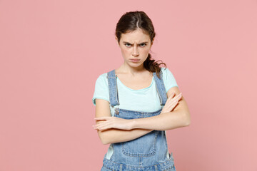 Wall Mural - Young frowning serious angry caucasian woman wear trendy denim clothes blue t-shirt look camera hold hands crossed folded isolated on pastel pink background studio portrait. People lifestyle concept.