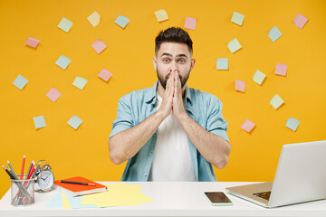 Canvas Print - Young shocked confused employee business man in blue shirt sit work at white office desk with pc laptop cover mouth with hands isolated on yellow background studio portrait Achievement career concept