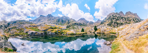 Fototapeta Pireneje  panoramiczny-widok-na-gorzysty-krajobraz-odbijajacy-sie-w-jeziorze-z-pieknymi-gorami-w-sloneczny-letni-dzien-koncepcja-wycieczki-gorskiej-circo-saboredo-dolina-aran-pireneje-katalonia-hiszpania