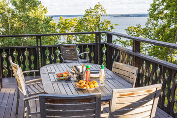 Beautiful view of patio with view on lake landscape. Dinner table with healthy grilled food. Sweden.