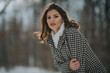 Beautiful Caucasian woman in a winter coat posing on the snowy field