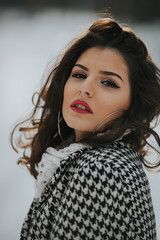 Poster - Beautiful Caucasian woman in a winter coat posing on the snowy field