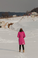 Sticker - Rear view of woman in a winter coat and bonnet walking on the snowy field