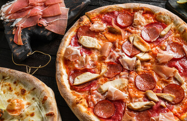 Canvas Print - Pizza Pepperoni with prosciutto, sausage, ham, cheese parmesan, tomatoes on dark wooden background. Fast food lunch for picnic company, close up, selective focus