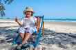 © CandyRetriever  - Healthy Asian senior woman resting on sunbed by the sea. Retirement elderly female sitting on beach chair relax and enjoy outdoor lifestyle activity at tropical island beach in summer holiday vacation