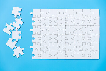 Wall Mural - Unfinished white jigsaw puzzle pieces on blue background, The last piece of jigsaw puzzle, Copy space.