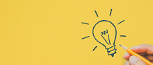 Hand Holding Pencil Drawing Light Bulb Yellow Background, Creative Idea, Innovation And Inspiration Concept, Copy Space