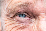 Fototapeta  - Close-up macro view on the blue eye of senior man smiling