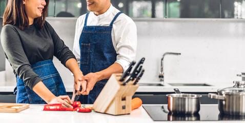 Wall Mural - Young asian family couple having fun cooking together with fresh vegetable salad on table.Happy couple prepare the yummy eating lunch in kitchen