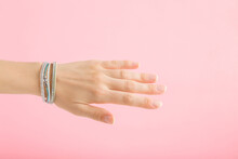 Bracelet Of Small Gems On Young Adult Woman Wrist Isolated On Light Pink Background. Pastel Color. Beautiful Groomed Hand. Closeup. Side View.
