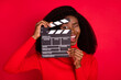 Photo of carefree crazy dark skin person hold clapboard near eye open mouth isolated on red color background