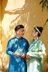 Poster - Young Vietnamese groom and bride standing outdoors and looking at each other with love and tender