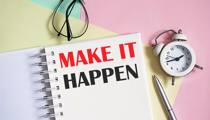 MAKE IT HAPPEN on the notebook with pen,alarm clock on pink background