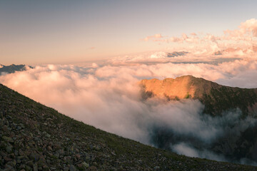 Wall Mural - The top of a mountain range surrounded by thick clouds in the evening in the Mukhinsky gorge of the Teberda nature reserve.