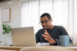 © eggeeggjiew - African American man having video conference with colleague at home. Black African Male freelancer using laptop in online meeting