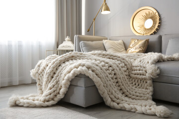 cozy living room interior with knitted blanket on comfortable sofa