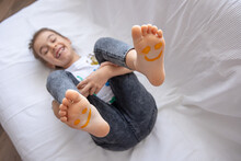 Close Up Of Little Girl's Feet Painted With Smiles.
