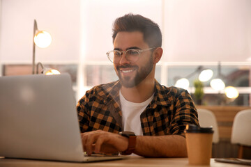 Wall Mural - Man working with laptop at table in cafe