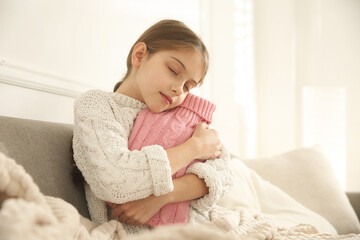 Ill girl with hot water bottle suffering from cold at home