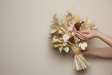 Canvas Print - Woman holding beautiful dried flower bouquet on beige background, closeup. Space for text