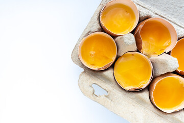 Close-up of fresh chicken eggs yolks in a shell on cardboard tray. Top view. Flat lay