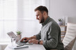 © New Africa - Young man working on laptop at table in office