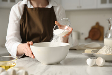 Wall Mural - Woman making dough at table in kitchen, closeup