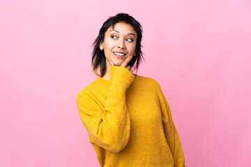 Wall Mural - Young Uruguayan woman over isolated pink background looking up while smiling