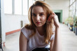© Artem Zatsepilin - young caucasian girl sits in t-shirt at coridor with windows and houseplants