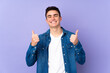© luismolinero - Teenager caucasian  handsome man isolated on purple background with thumbs up gesture and smiling