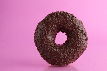 Wall Mural - Chocolate berliner doughnut on a pink background with a place to text a copyspace breakfast dessert national dish