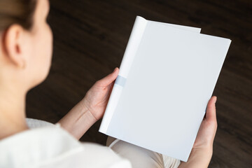 top view of a woman reading an open book or magazine. empty page. mock up