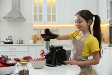 Canvas Print - Little girl using modern meat grinder in kitchen