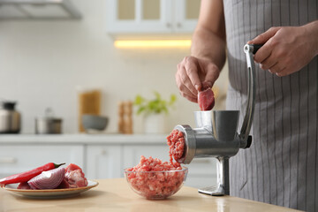 Canvas Print - Man using hand meat grinder in kitchen, closeup