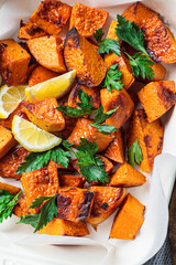 Wall Mural - Close up of baked sweet potato wedges with lemon and parsley in baking dish.