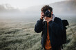 Junger Fotograf fotografiert morgens eine neblige Landschaft