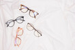 canvas print picture - multiple eyes glasses on white crumpled fabric copy space top view
