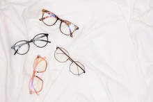 Multiple Eyes Glasses On White Crumpled Fabric Copy Space Top View