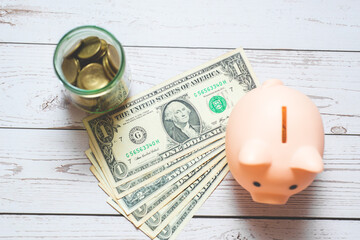 money saving or financial and banking for business investment concept. bank note us dollar with piggy bank and coin in glass jar and calculator on wood table.