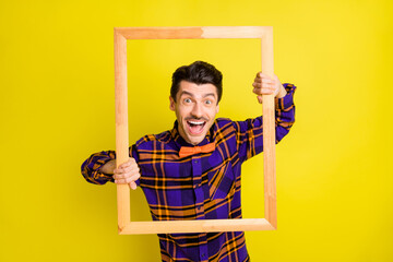 Sticker - Photo of young excited man happy positive smile hold border frame make snapshot isolated over yellow color background